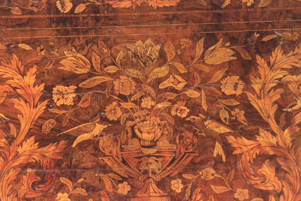 An antique Dutch marquetry chest of drawers featuring three drawers, floral wood inlay, shaped sides, and brass drop handles. View XII