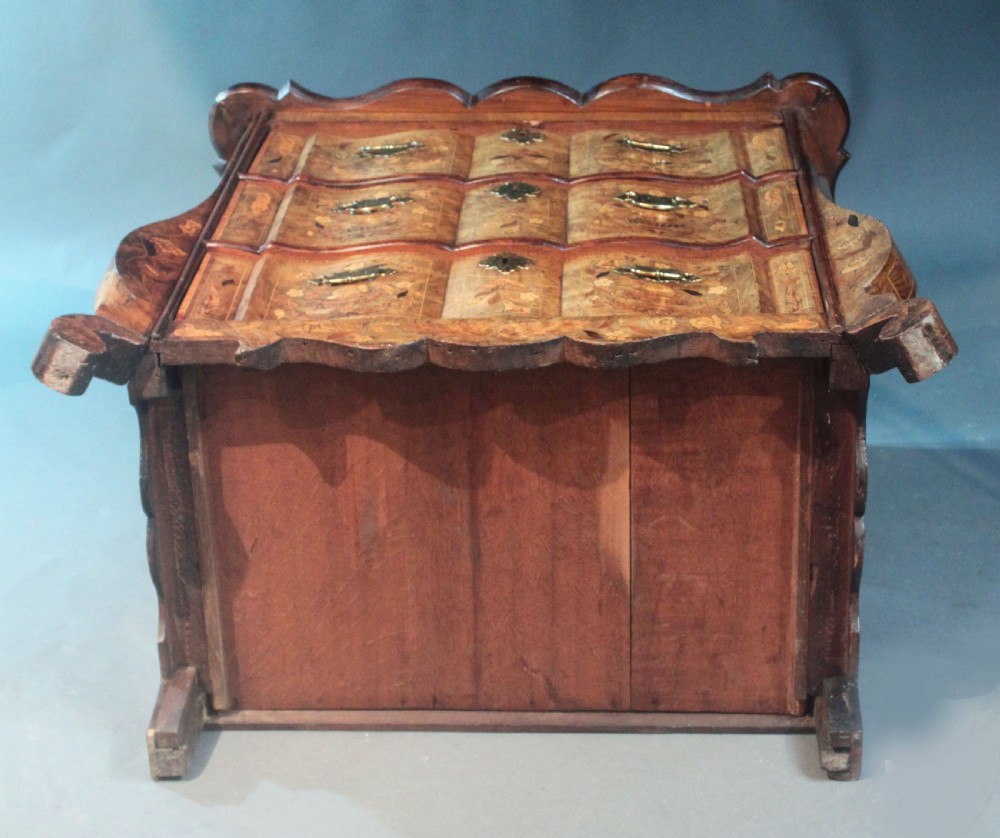 An antique Dutch marquetry chest of drawers featuring three drawers, floral wood inlay, shaped sides, and brass drop handles. View XVI