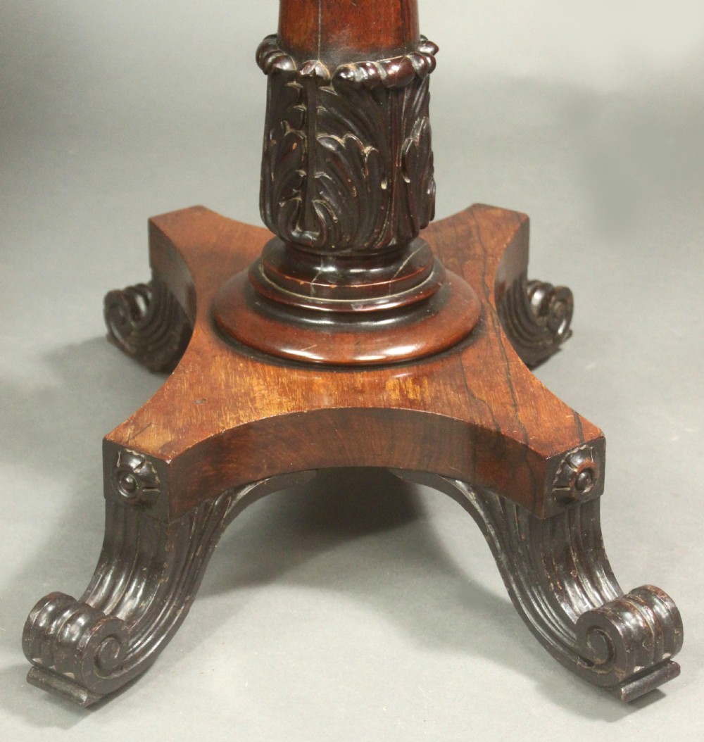 A Regency rosewood occasional table featuring a rectangular top, a tapered carved column support, and a quadform base on scroll feet. View VII