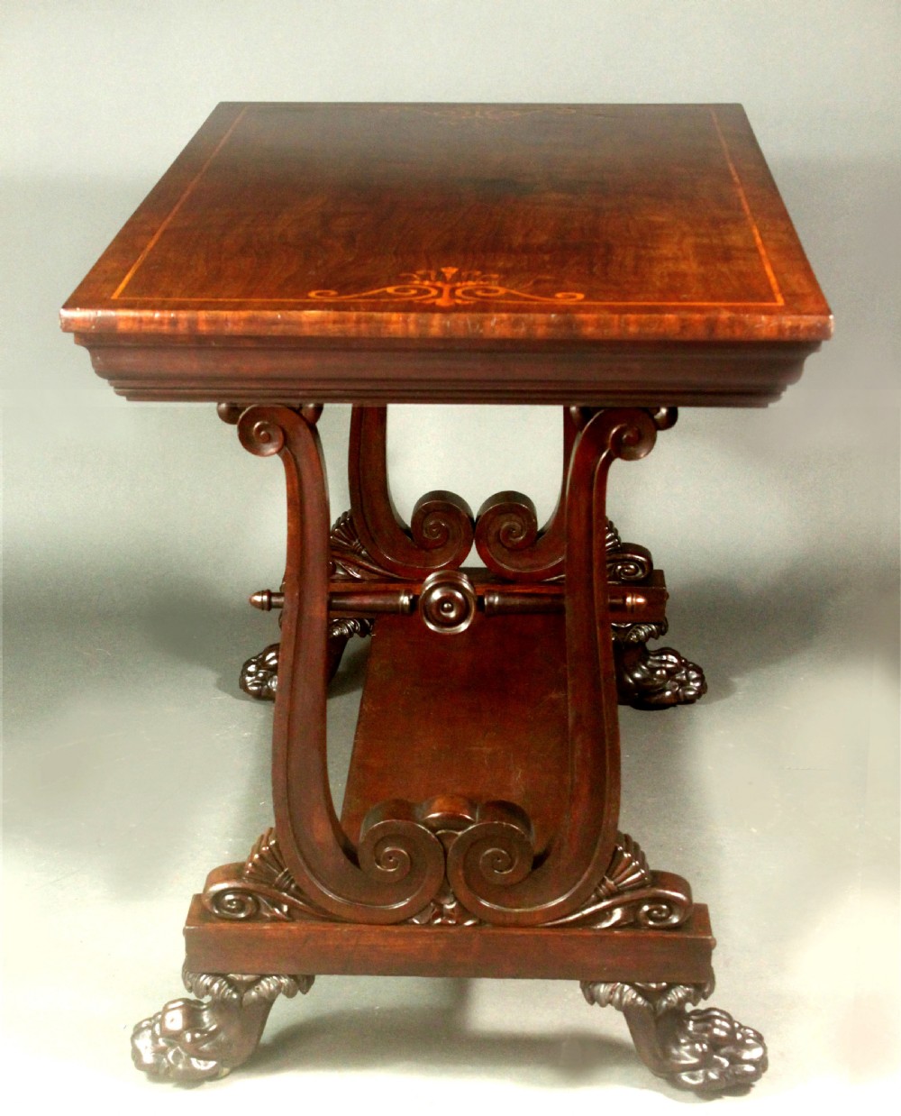 A rectangular Regency mahogany centre table featuring corner inlay, carved scroll supports, a lower stretcher shelf, and carved lion paw feet. View III