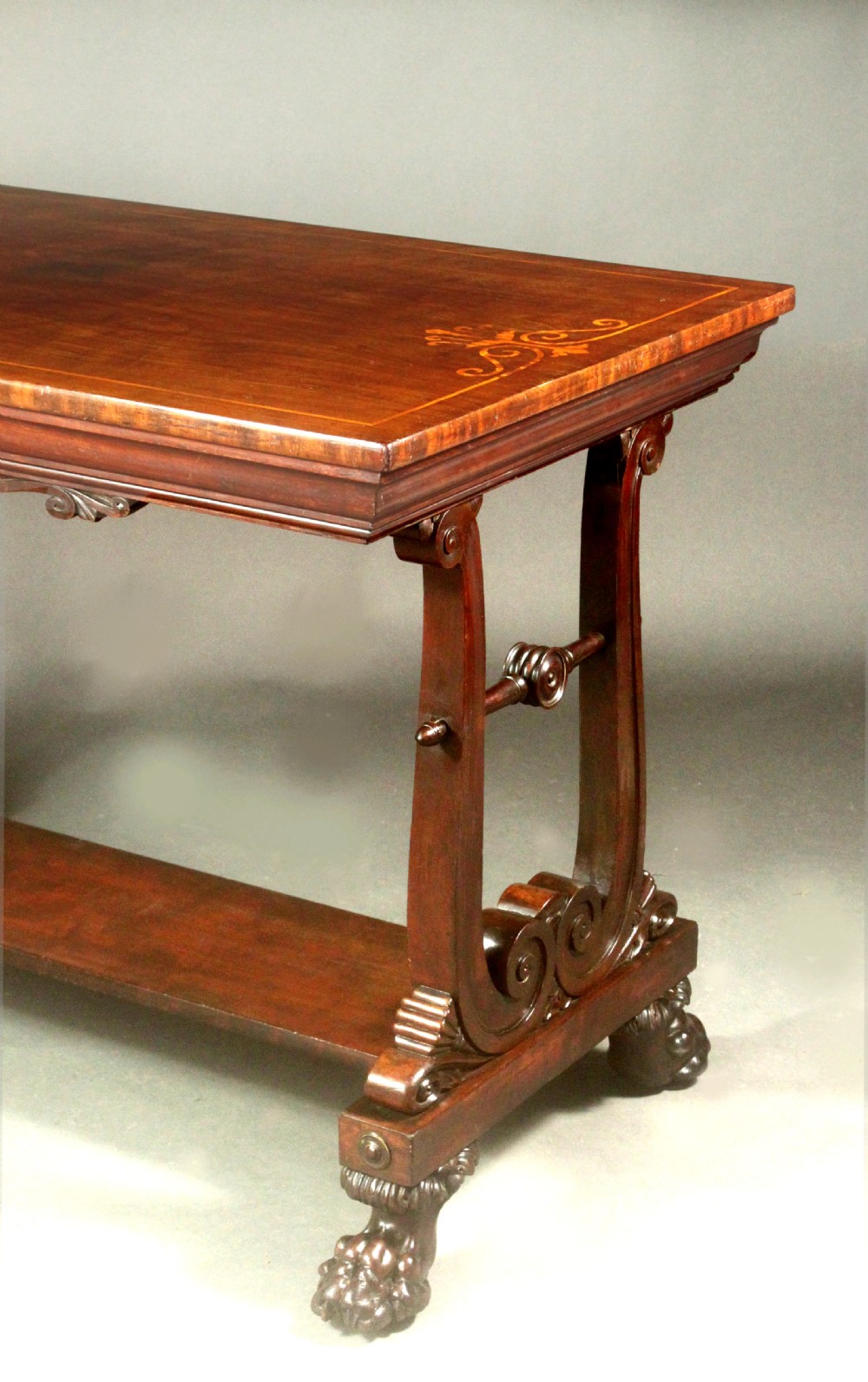 A rectangular Regency mahogany centre table featuring corner inlay, carved scroll supports, a lower stretcher shelf, and carved lion paw feet. View V