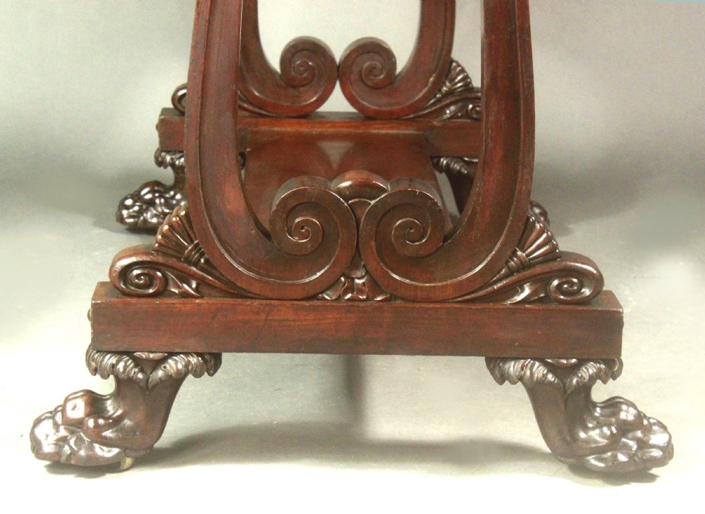 A rectangular Regency mahogany centre table featuring corner inlay, carved scroll supports, a lower stretcher shelf, and carved lion paw feet. View VI