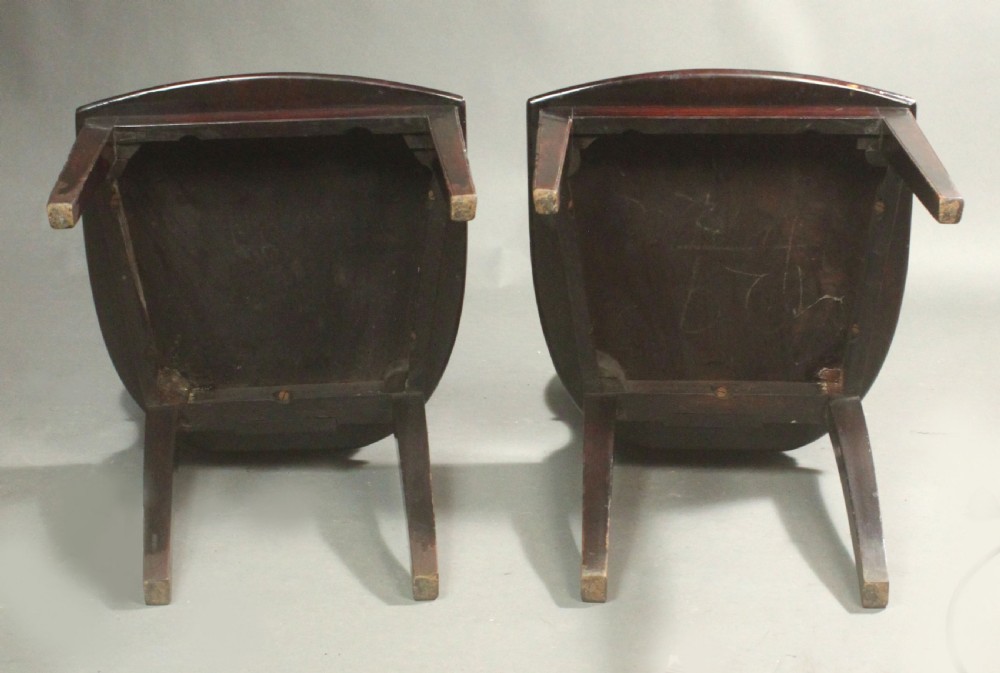 A pair of George III mahogany hall chairs featuring oval backrests with central painted armorial crests, solid timber seats, and square tapered legs. View VII