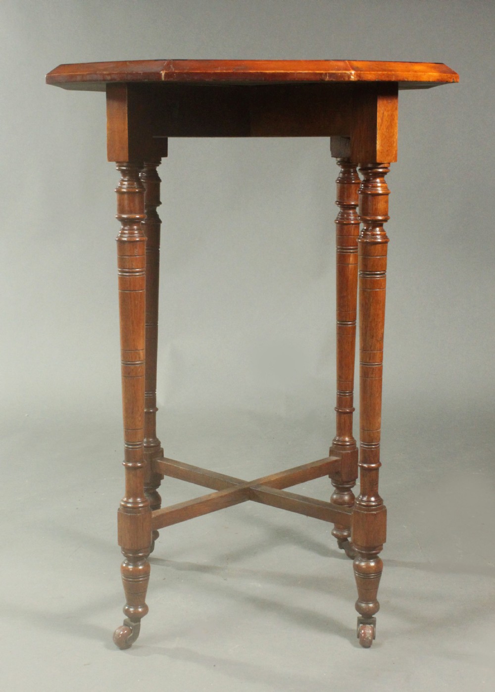 An octagonal side table featuring a central inlaid star pattern in contrasting timber veneers, set on turned legs with a cross-stretcher and castors. View VI