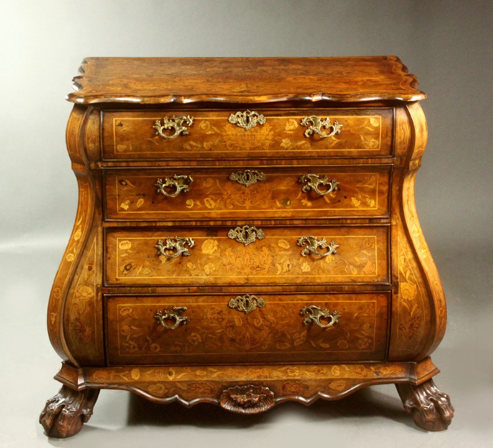 An antique Dutch walnut bombe chest featuring detailed floral marquetry inlays, four drawers, cast brass handles, and carved claw and ball feet.