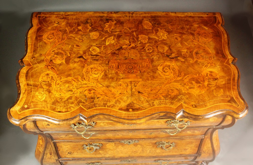 An antique Dutch walnut bombe chest featuring detailed floral marquetry inlays, four drawers, cast brass handles, and carved claw and ball feet. View III