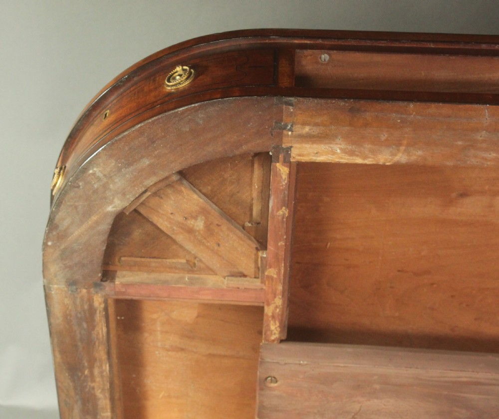 A Regency mahogany centre table featuring a rounded rectangular top, crossbanded border, drawer frieze with brass ring handles, and a reeded quadruped pedestal base with brass lion paw feet on castors. View V