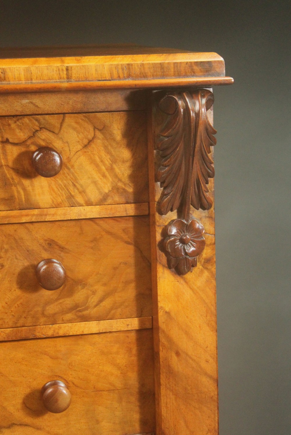A tall Victorian walnut Wellington chest featuring seven graduated drawers with turned wooden knobs, carved upper corbels, and a right-hand hinged locking flap. View XI