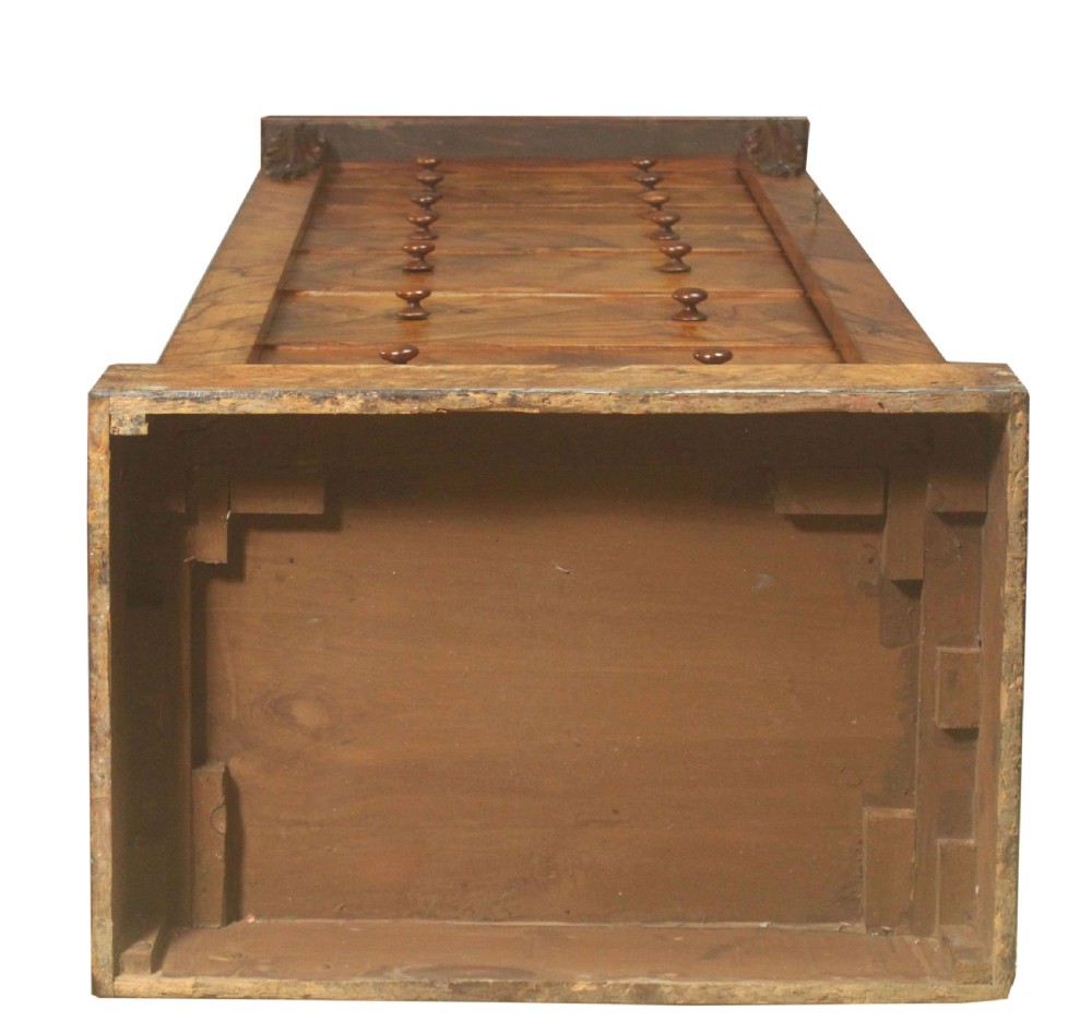 A tall Victorian walnut Wellington chest featuring seven graduated drawers with turned wooden knobs, carved upper corbels, and a right-hand hinged locking flap. View XII