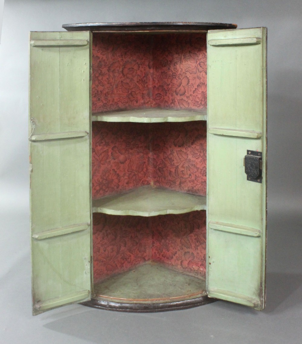 An antique painted hanging corner cupboard featuring a detailed figurative scene with a crowned monarch, courtiers, drapery, and a chequerboard floor across its two doors. View III