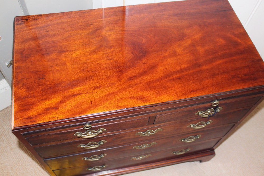 An antique Georgian mahogany caddy-top chest of drawers featuring a pull-out brushing slide, decorative brass handles, and bracket feet. View III