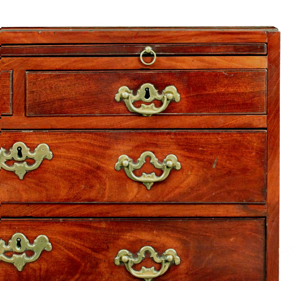 An antique Georgian mahogany caddy-top chest of drawers featuring a pull-out brushing slide, decorative brass handles, and bracket feet. View VI