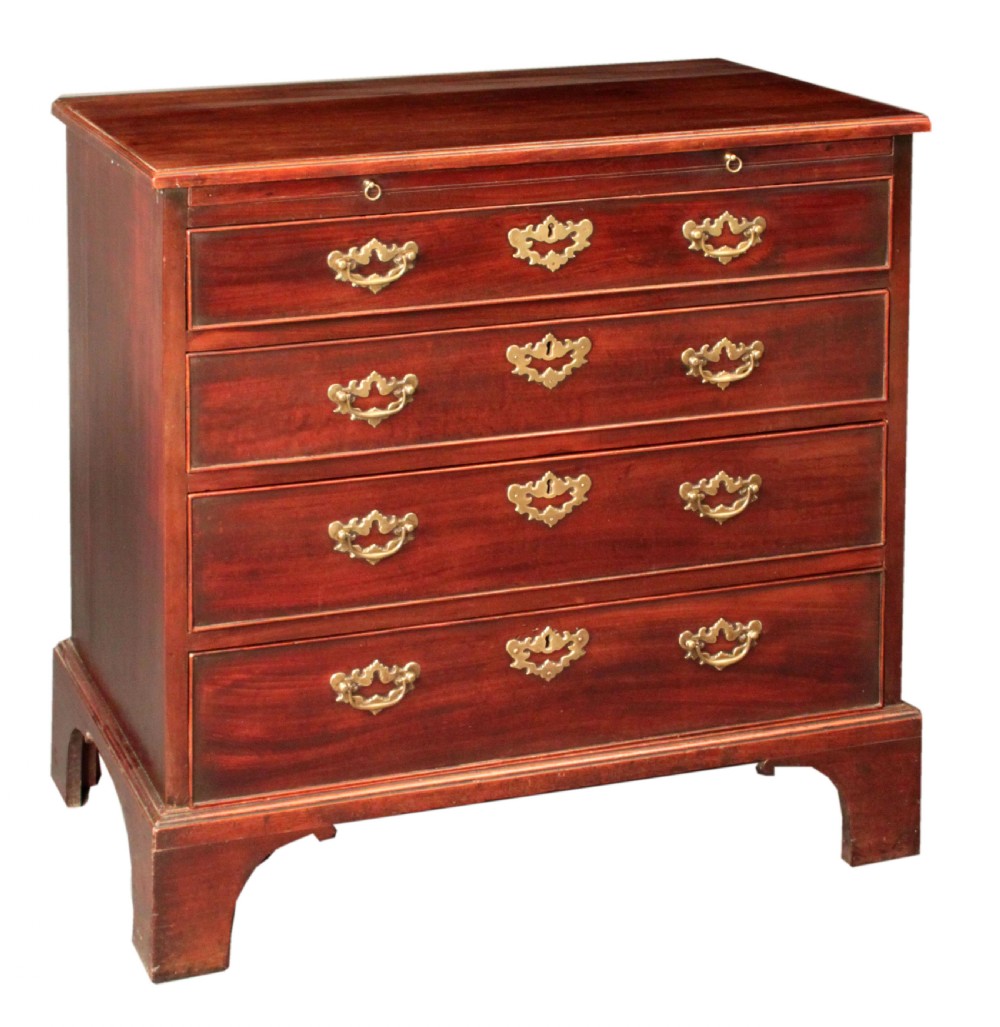 A Georgian mahogany chest featuring four graduated drawers, brass batwing escutcheons and handles, a brushing slide, and bracket feet.