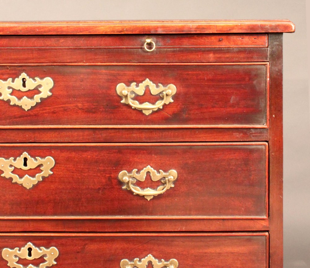 A Georgian mahogany chest featuring four graduated drawers, brass batwing escutcheons and handles, a brushing slide, and bracket feet. View II