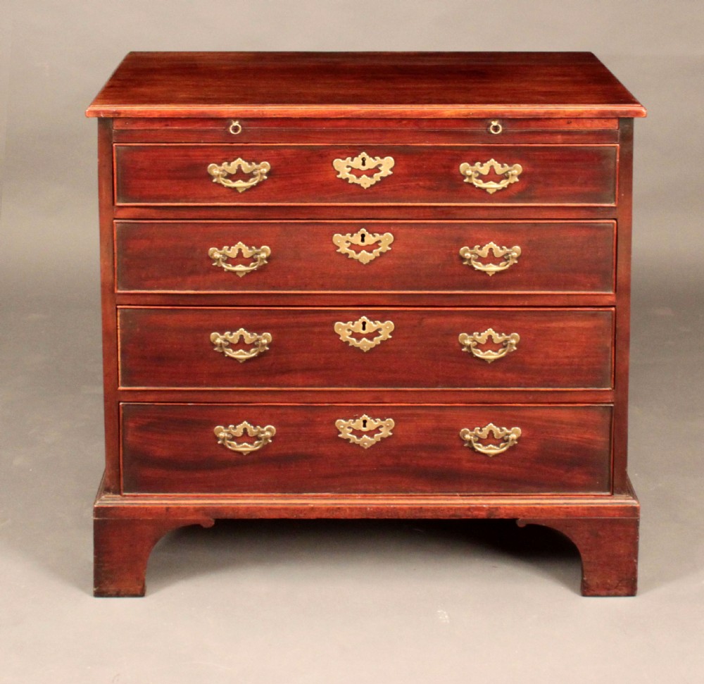 A Georgian mahogany chest featuring four graduated drawers, brass batwing escutcheons and handles, a brushing slide, and bracket feet. View III