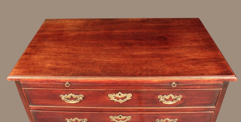 A Georgian mahogany chest featuring four graduated drawers, brass batwing escutcheons and handles, a brushing slide, and bracket feet. View IV