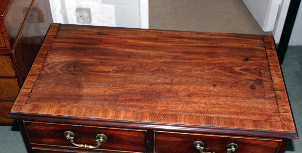 A Georgian Chippendale mahogany chest of drawers featuring two short over three long drawers with brass swan-neck handles and bracket feet. View III