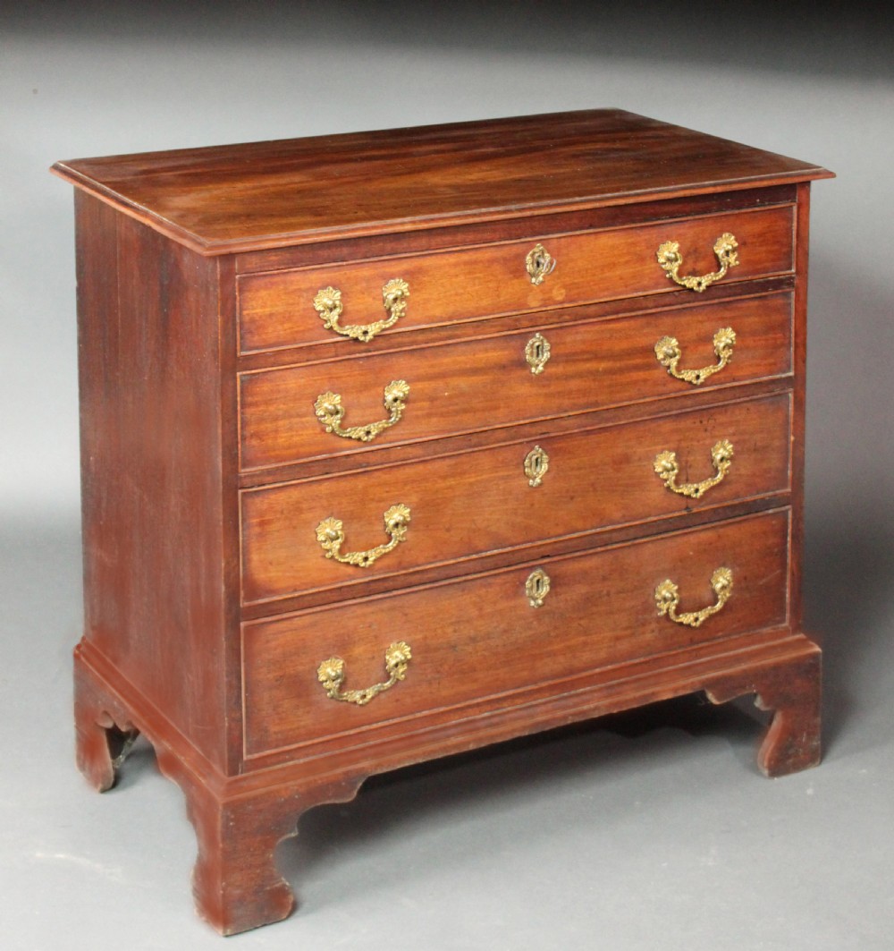 A Chippendale mahogany chest of drawers with four graduated drawers, brass rococo handles, keyhole escutcheons, and shaped bracket feet.