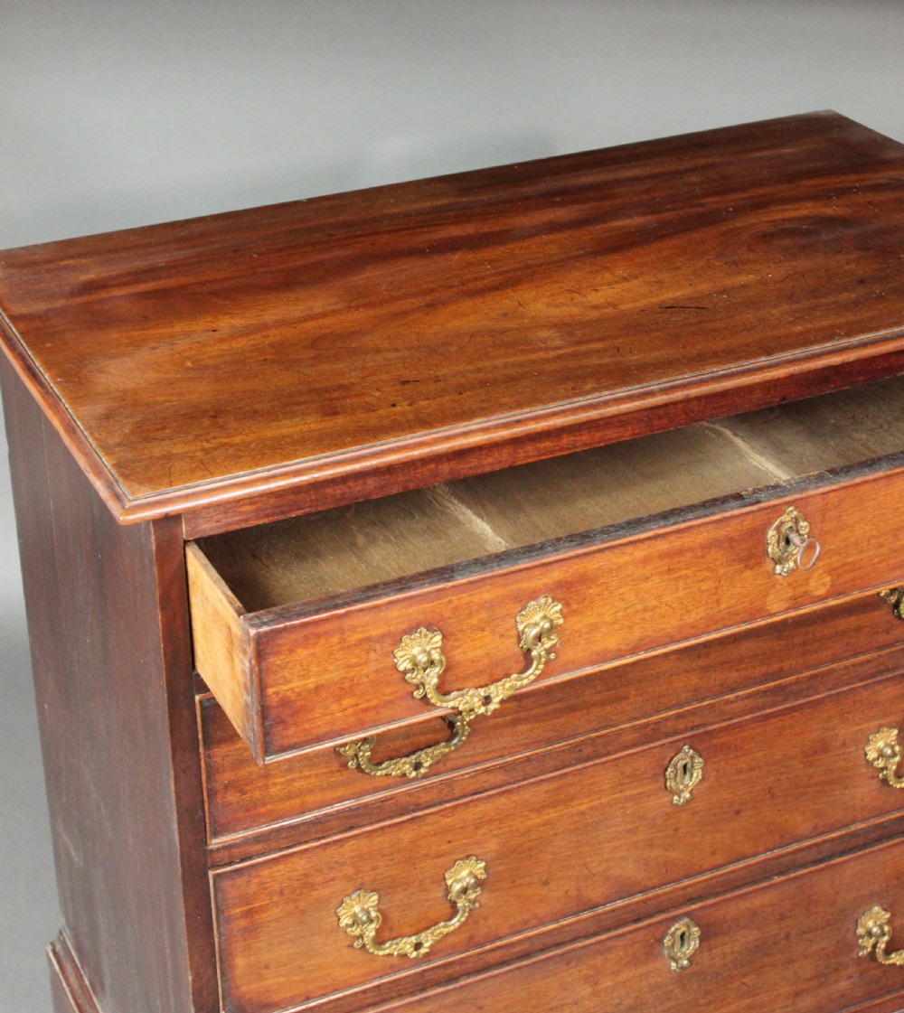 A Chippendale mahogany chest of drawers with four graduated drawers, brass rococo handles, keyhole escutcheons, and shaped bracket feet. View III