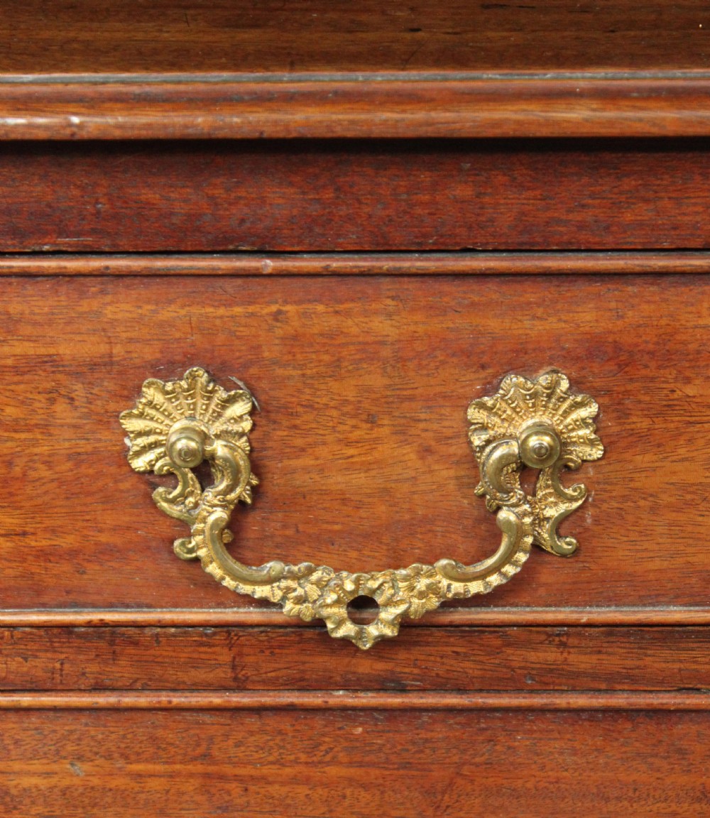 A Chippendale mahogany chest of drawers with four graduated drawers, brass rococo handles, keyhole escutcheons, and shaped bracket feet. View V