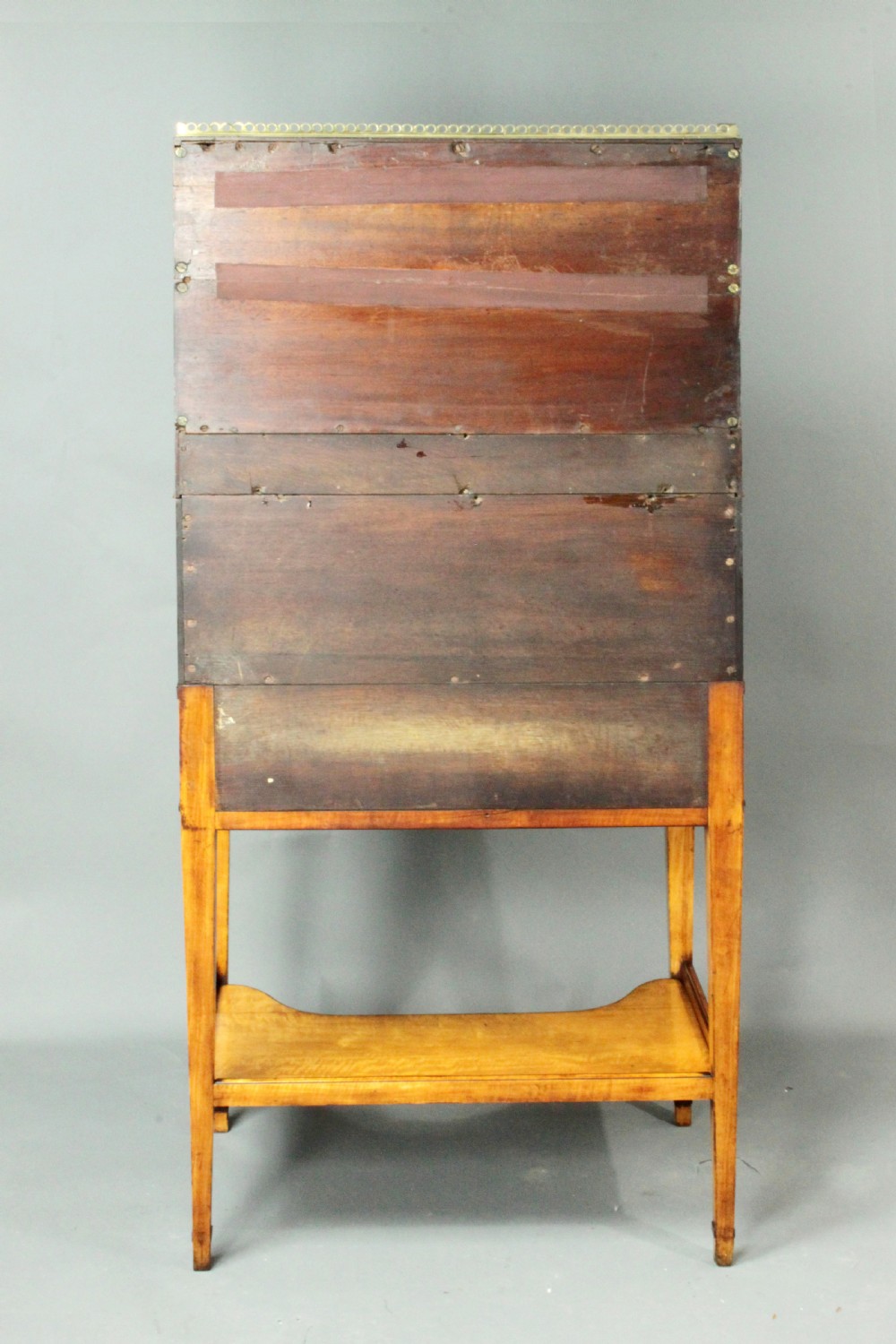 An antique satinwood cylinder bureau desk featuring an open two-tier bookshelf gallery at the top, a green leather writing surface inside, and tapered square legs with a low shelf. View VII