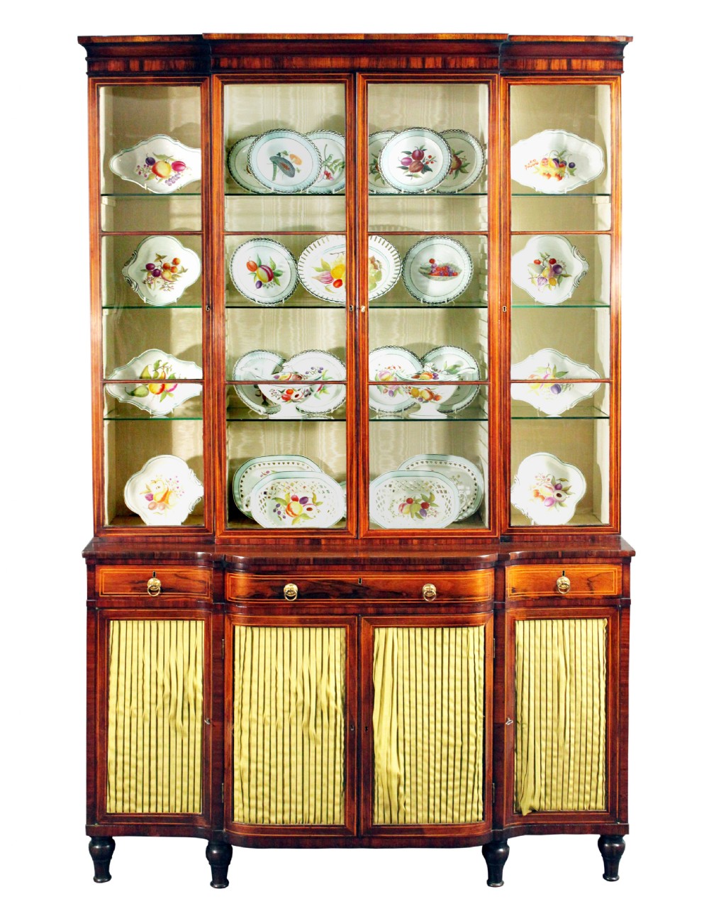 A Regency rosewood breakfront bookcase featuring four glazed upper doors and four lower doors lined with pleated fabric.