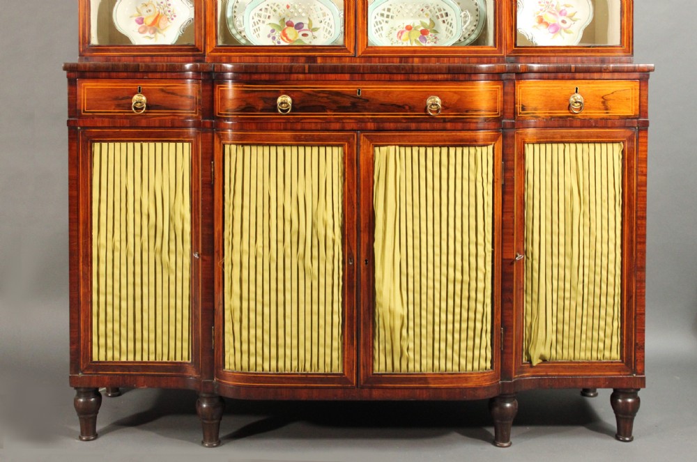 A Regency rosewood breakfront bookcase featuring four glazed upper doors and four lower doors lined with pleated fabric. View II