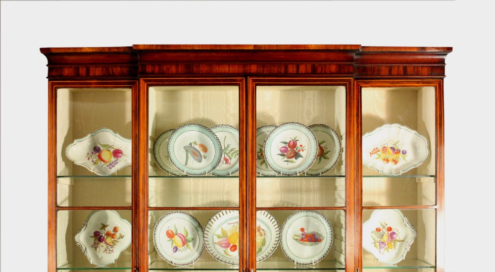 A Regency rosewood breakfront bookcase featuring four glazed upper doors and four lower doors lined with pleated fabric. View V