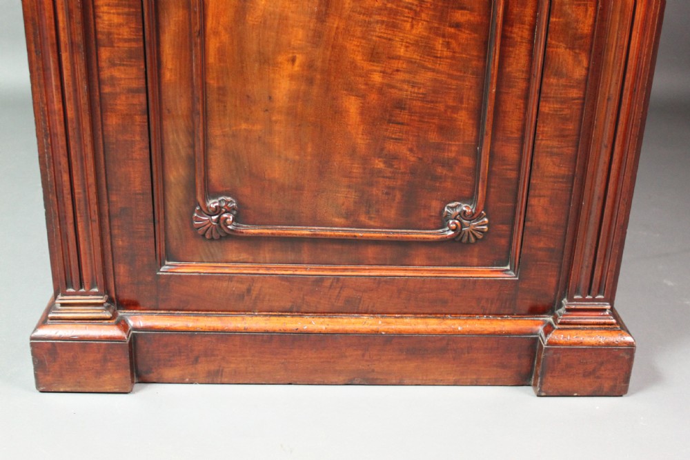 A nineteenth-century flame mahogany library cabinet featuring carved pilasters, reeded side columns, and a single recessed panel door set on a solid plinth base. View VII