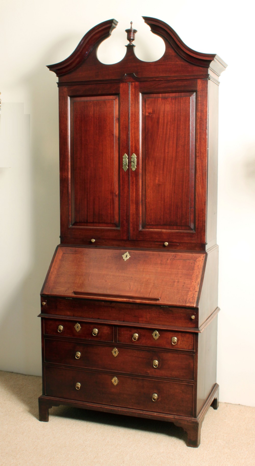 A Georgian mahogany bureau bookcase featuring a swan-neck pediment top, twin panelled upper doors, a slant-front writing bureau with fitted pigeonholes, and three base drawers on bracket feet. View III