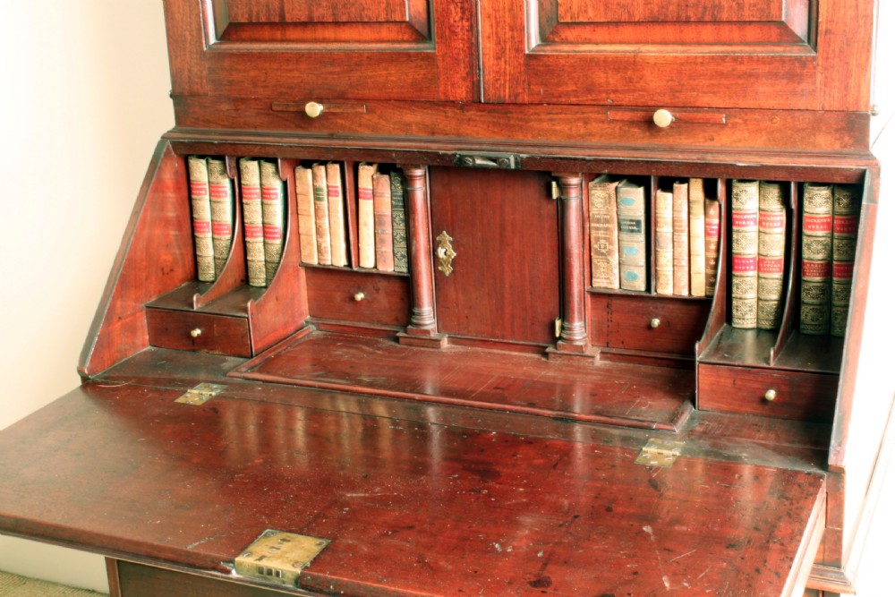 A Georgian mahogany bureau bookcase featuring a swan-neck pediment top, twin panelled upper doors, a slant-front writing bureau with fitted pigeonholes, and three base drawers on bracket feet. View VIII