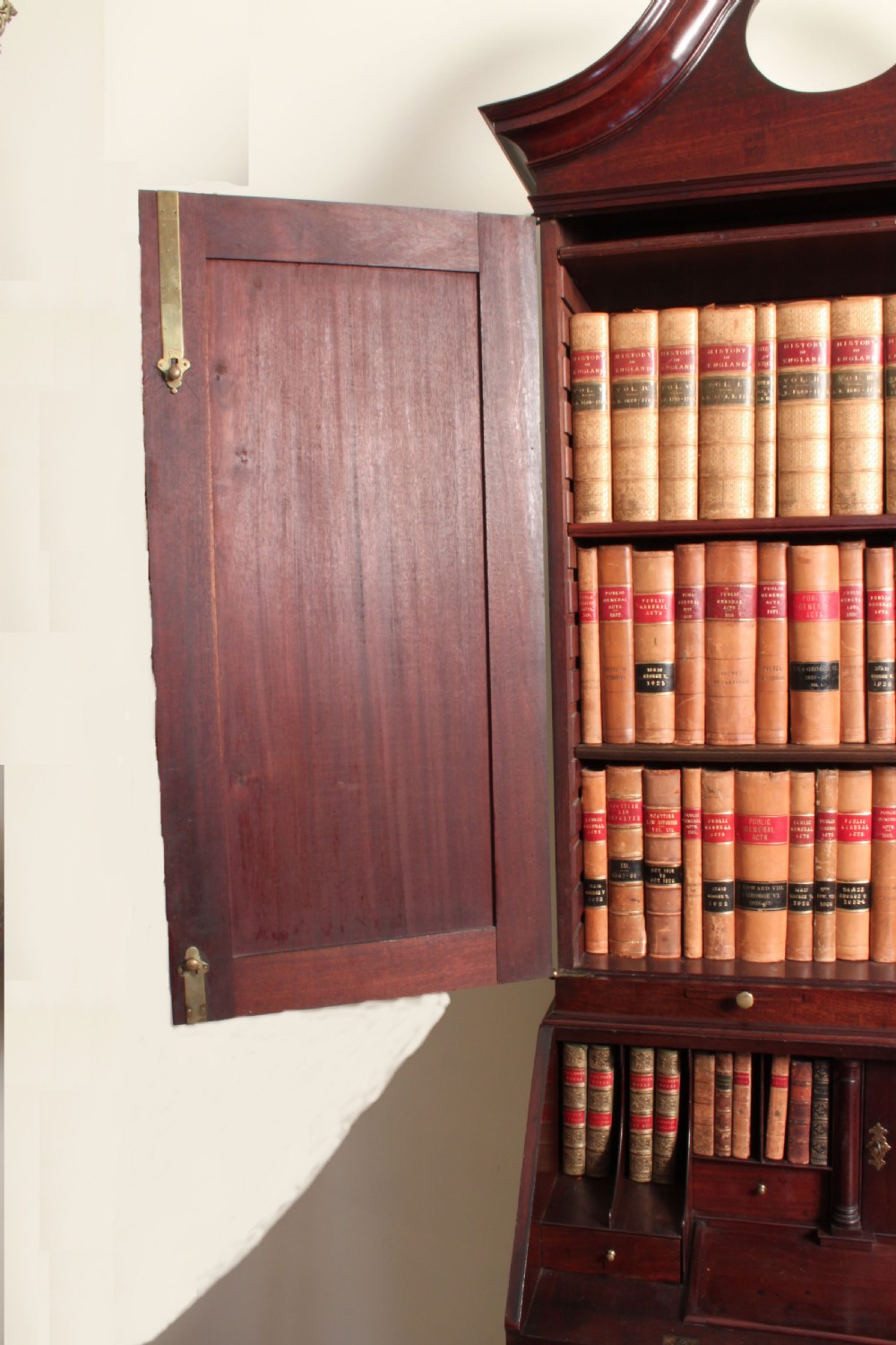 A Georgian mahogany bureau bookcase featuring a swan-neck pediment top, twin panelled upper doors, a slant-front writing bureau with fitted pigeonholes, and three base drawers on bracket feet. View X