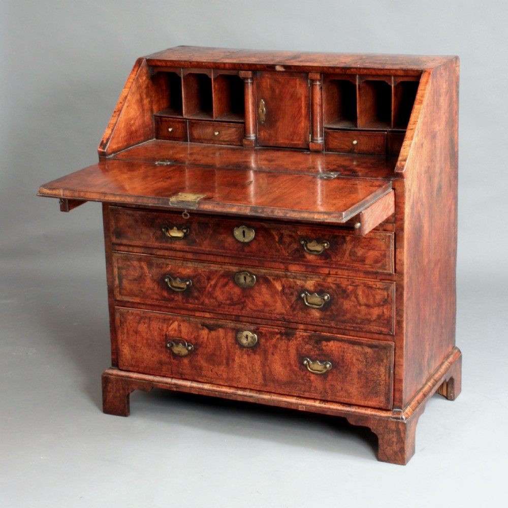 An early 18th-century George I walnut bureau featuring a sloping fall-front lid above four graduated drawers with brass drop handles and bracket feet. View III