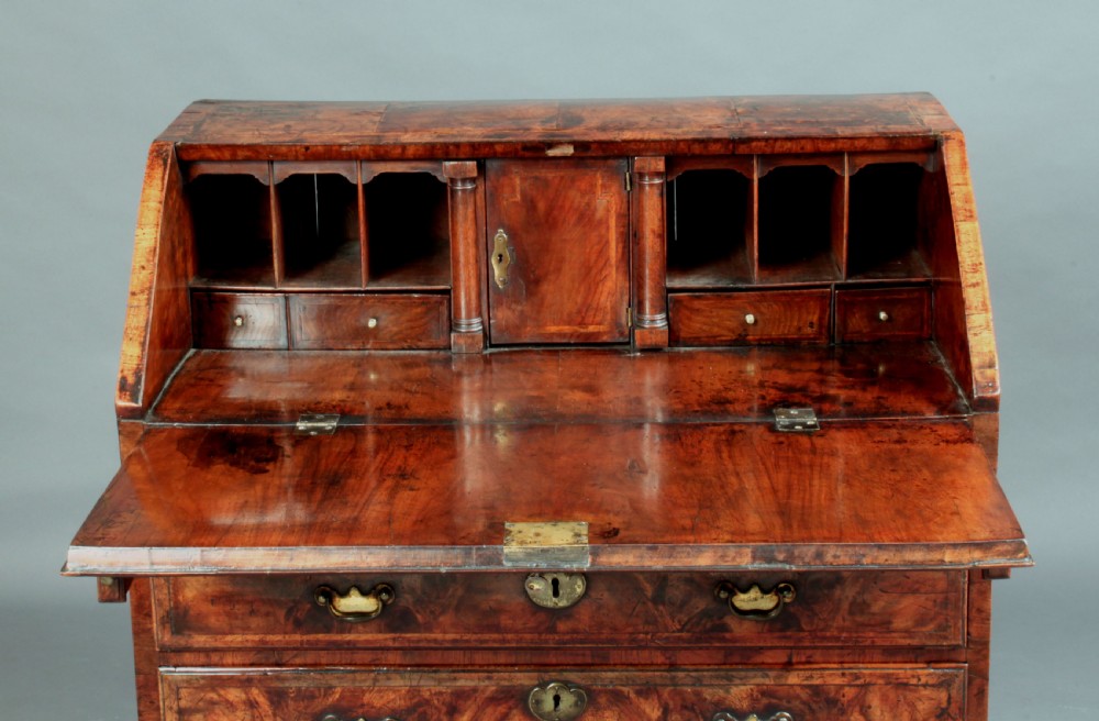 An early 18th-century George I walnut bureau featuring a sloping fall-front lid above four graduated drawers with brass drop handles and bracket feet. View IV