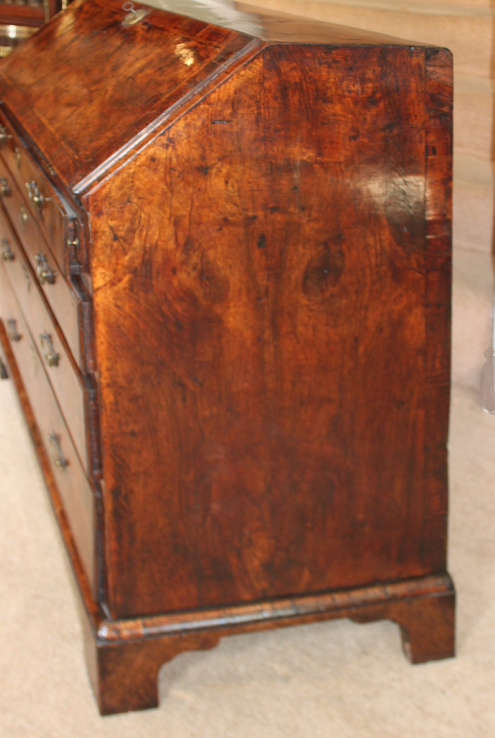 An early 18th-century George I walnut bureau featuring a sloping fall-front lid above four graduated drawers with brass drop handles and bracket feet. View V