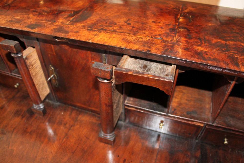 An early 18th-century George I walnut bureau featuring a sloping fall-front lid above four graduated drawers with brass drop handles and bracket feet. View VI