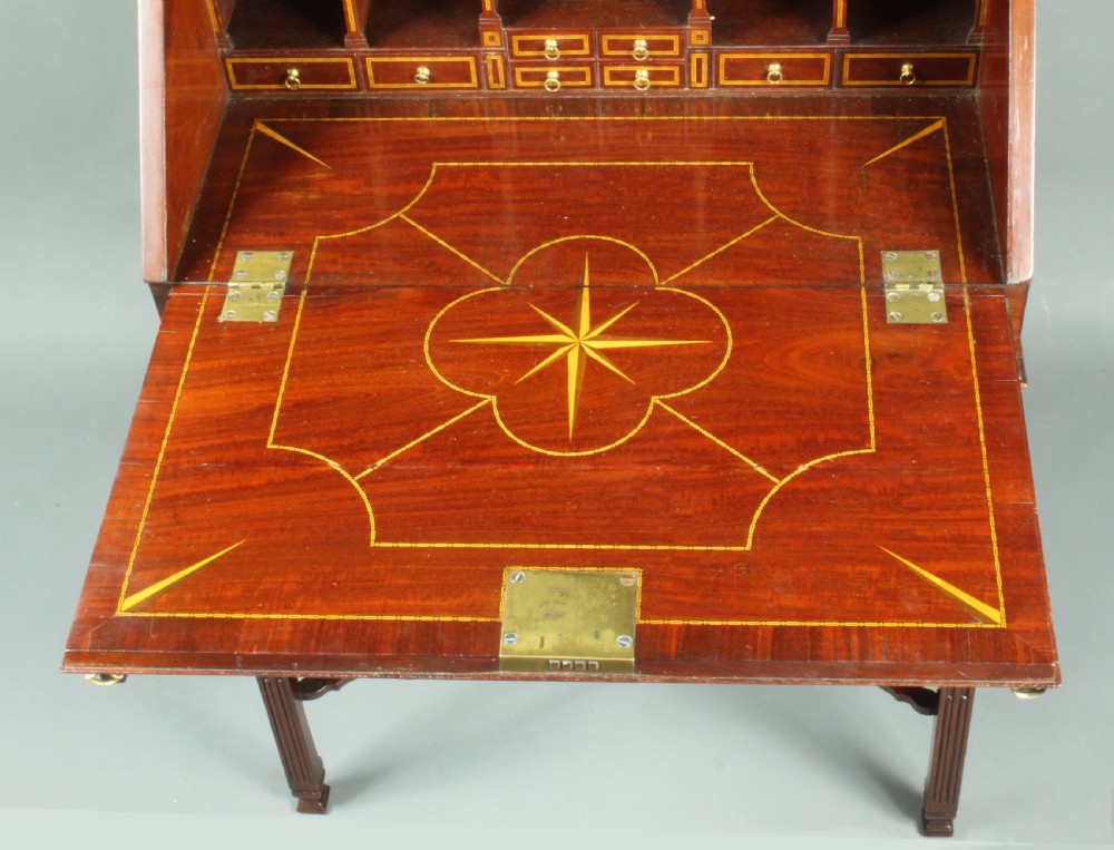 An antique Chippendale style dark mahogany slant-front bureau mounted on a tall stand with straight carved legs and an X-frame stretcher. View IV