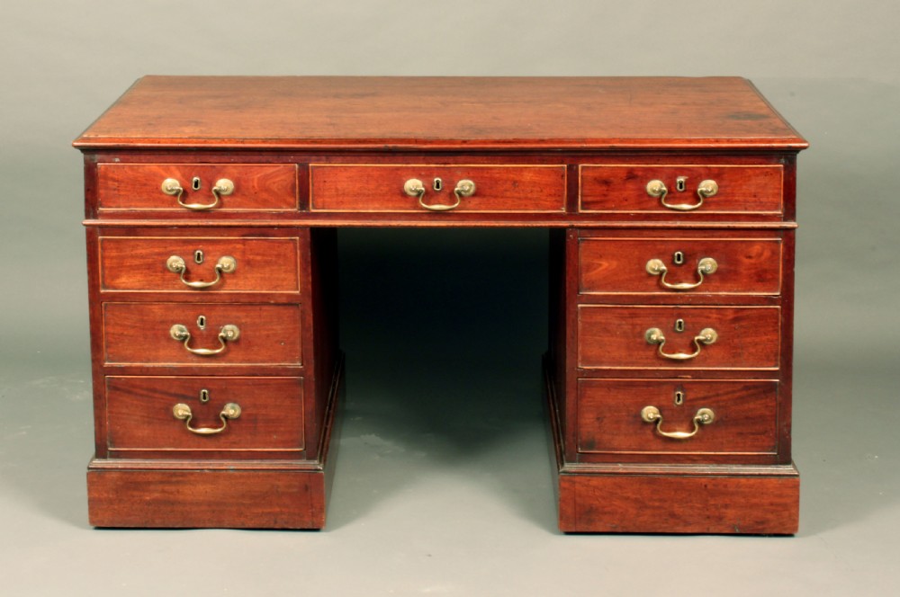 An antique Chippendale mahogany pedestal desk featuring nine cockbeaded drawers with brass swan-neck handles around a central kneehole, resting on twin plinth bases. View II
