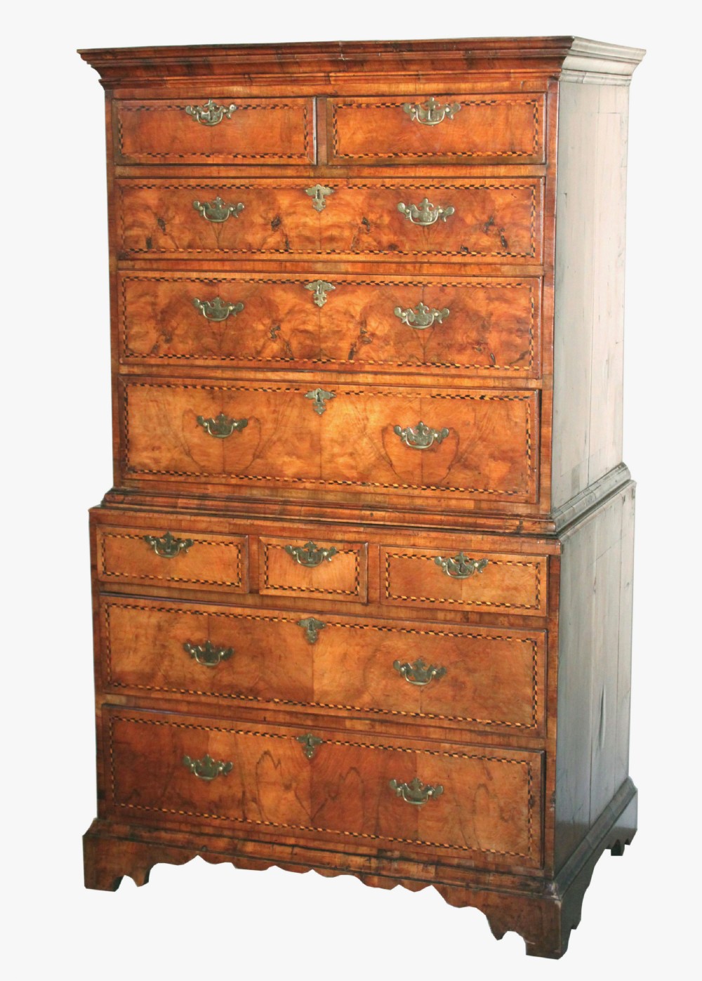 An eighteenth-century burr walnut tallboy chest-on-chest with feather-banded drawer fronts, brass handles, and bracket feet.