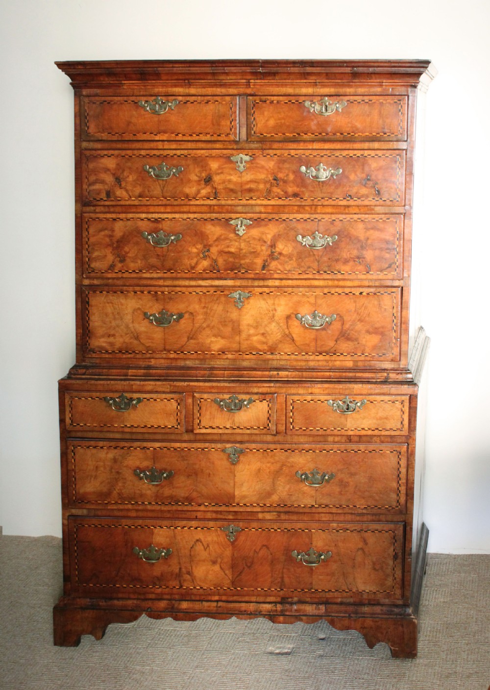 An eighteenth-century burr walnut tallboy chest-on-chest with feather-banded drawer fronts, brass handles, and bracket feet. View II