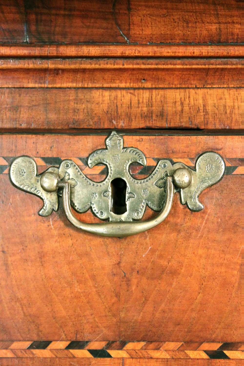 An eighteenth-century burr walnut tallboy chest-on-chest with feather-banded drawer fronts, brass handles, and bracket feet. View V