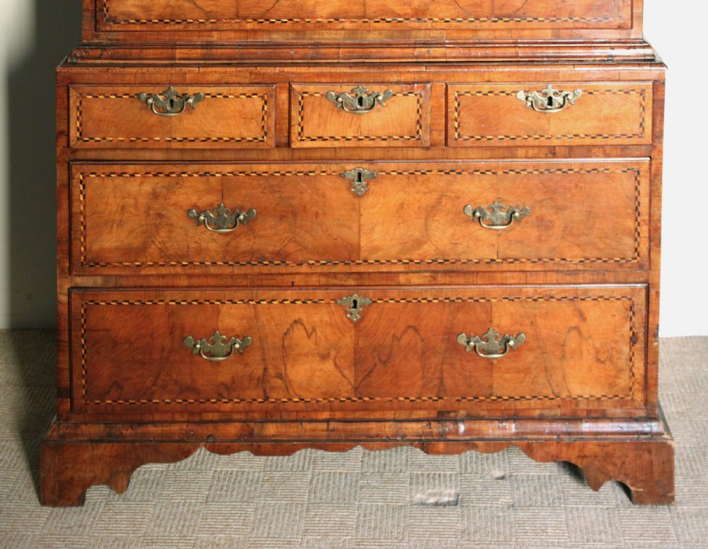 An eighteenth-century burr walnut tallboy chest-on-chest with feather-banded drawer fronts, brass handles, and bracket feet. View X