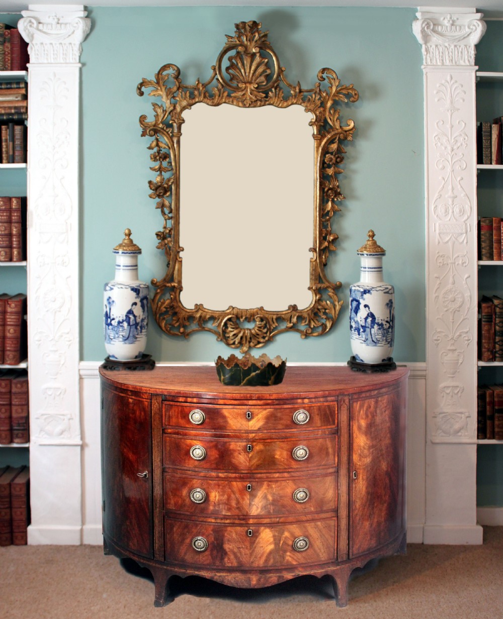 A late 18th-century George III flame mahogany demi-lune commode featuring four central drawers flanked by side cupboards, resting on bracket feet. View II