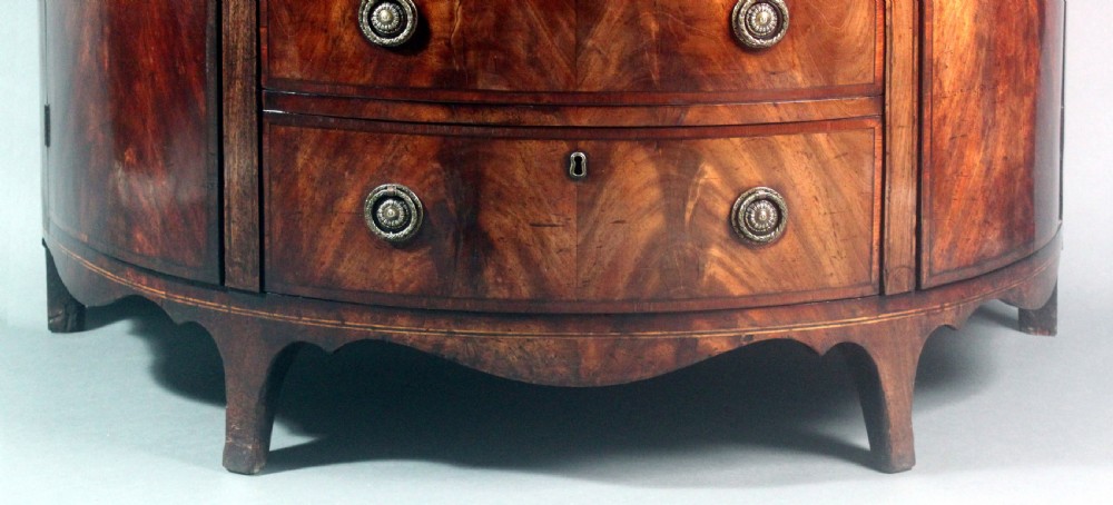 A late 18th-century George III flame mahogany demi-lune commode featuring four central drawers flanked by side cupboards, resting on bracket feet. View X