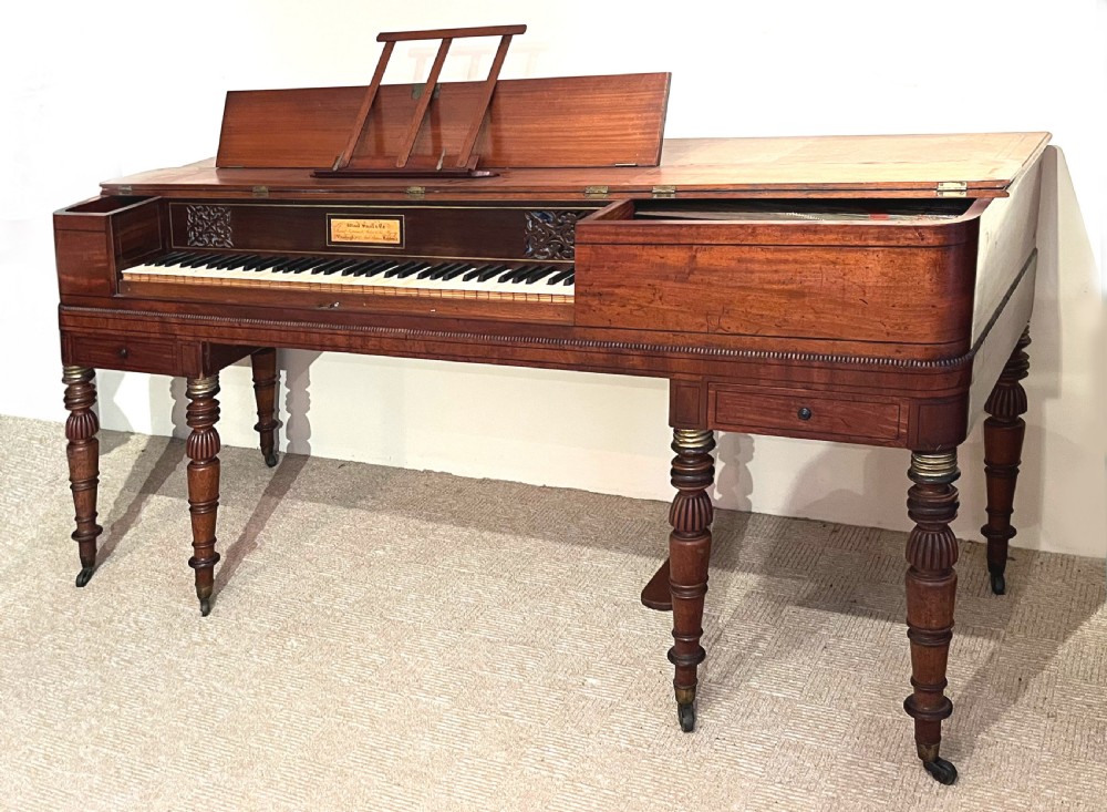 A Regency mahogany square piano crafted by Wood, Small and Co, raised on turned reeded legs with brass castors and featuring an open music rest.