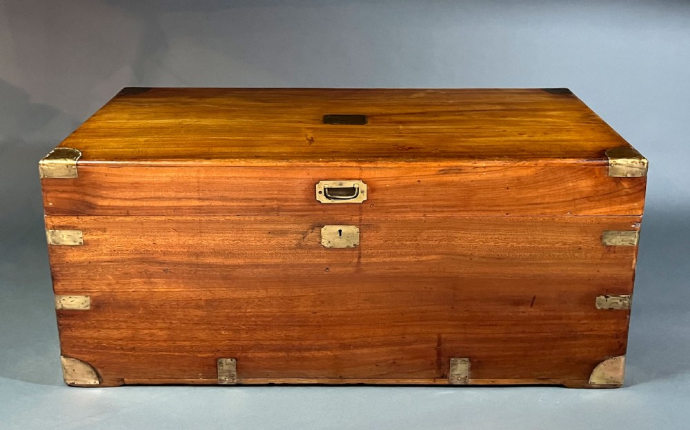 An antique rectangular camphor wood campaign chest featuring recessed brass handles, corner brackets, and a central brass escutcheon. View II