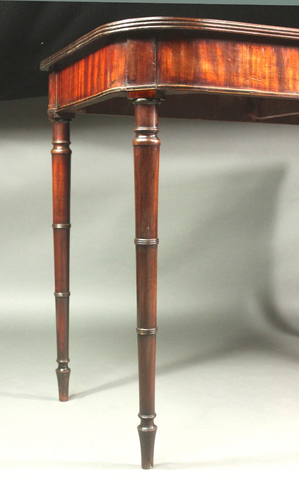 A matching pair of Georgian mahogany serving tables featuring flame veneer aprons and turned tapered legs. View III