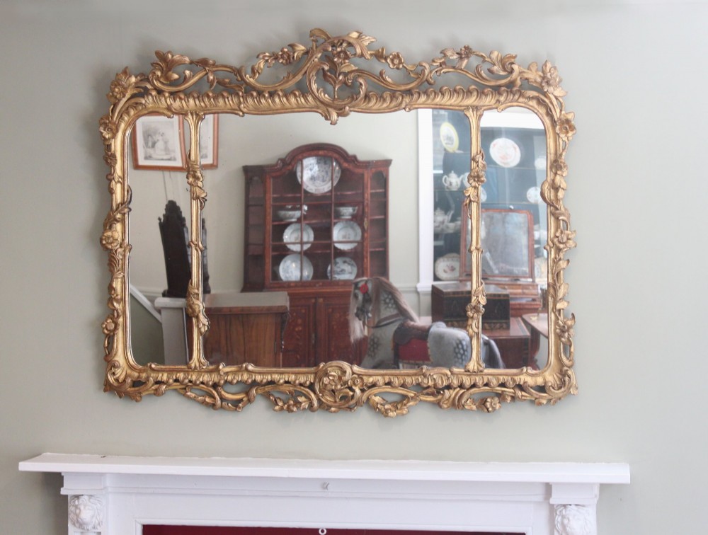 An ornate horizontal Chippendale giltwood overmantel mirror featuring intricate floral and leaf carvings around three glass panels. View II