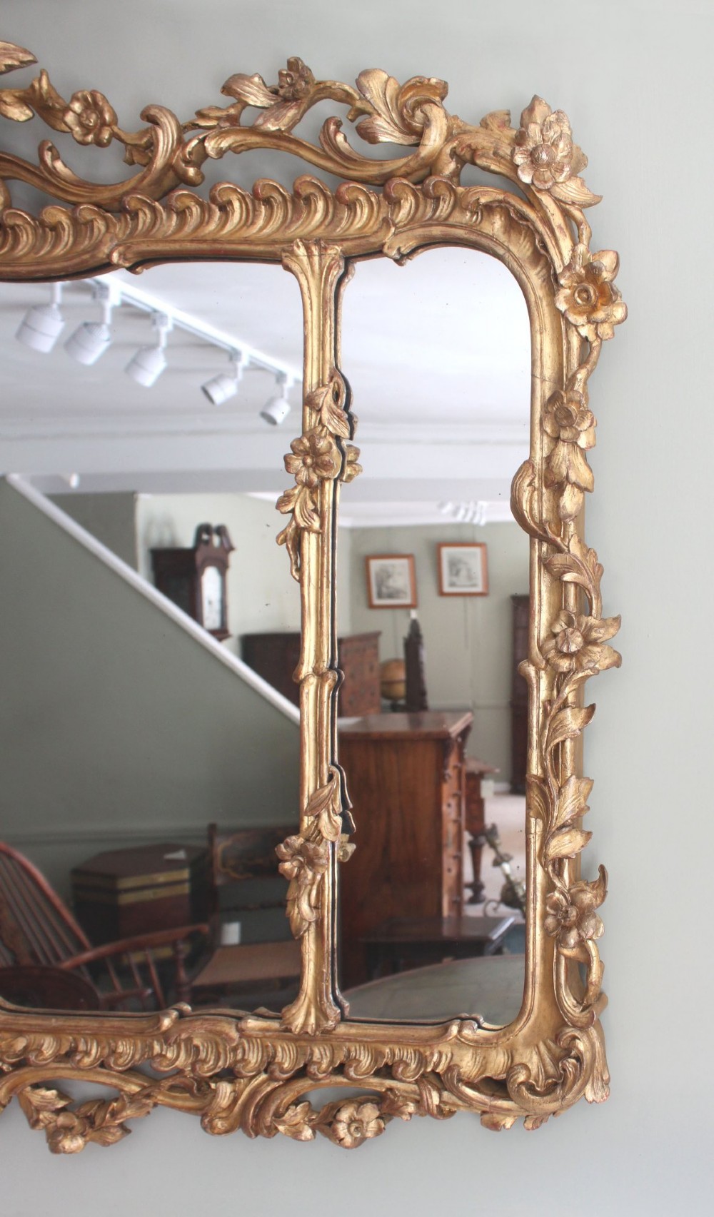 An ornate horizontal Chippendale giltwood overmantel mirror featuring intricate floral and leaf carvings around three glass panels. View IV