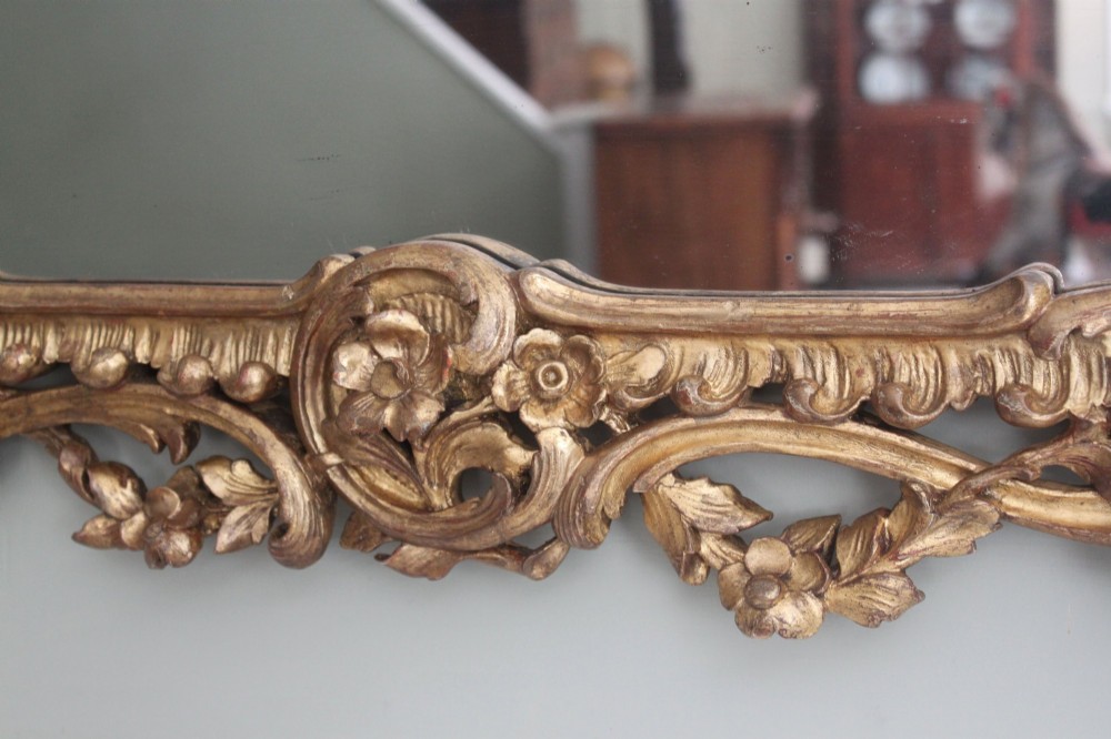An ornate horizontal Chippendale giltwood overmantel mirror featuring intricate floral and leaf carvings around three glass panels. View VII